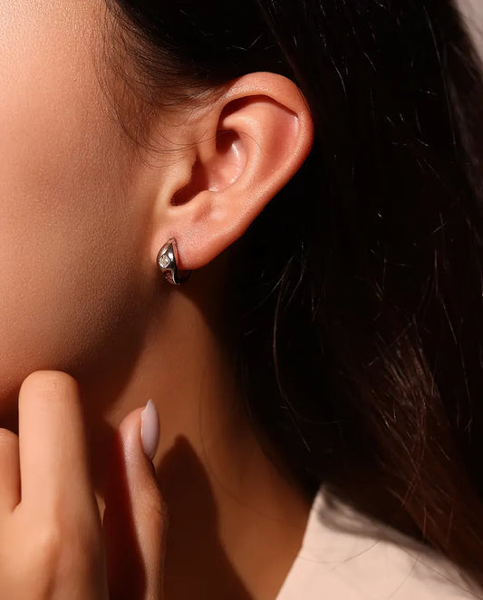 Asscher Cut Moissanite Huggie Hoop Earrings in 925 Sterling Silver - worn on a model’s ear, hand near her face
