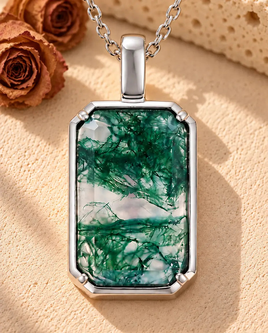 Rectangle Moss Agate Pendant Necklace in 925 Sterling Silver - lying on a cream textured surface beside a travertine block