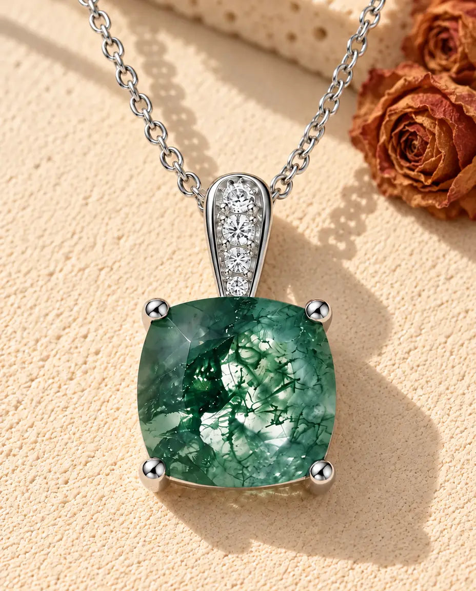 Cushion Moss Agate Pendant Necklace in 925 Sterling Silver - lying on a cream textured surface beside a travertine block