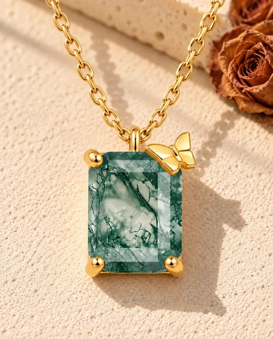 Emerald Cut Moss Agate Necklace in 10K Gold Plated 925 Sterling Silver - lying on a cream textured surface beside a travertine block