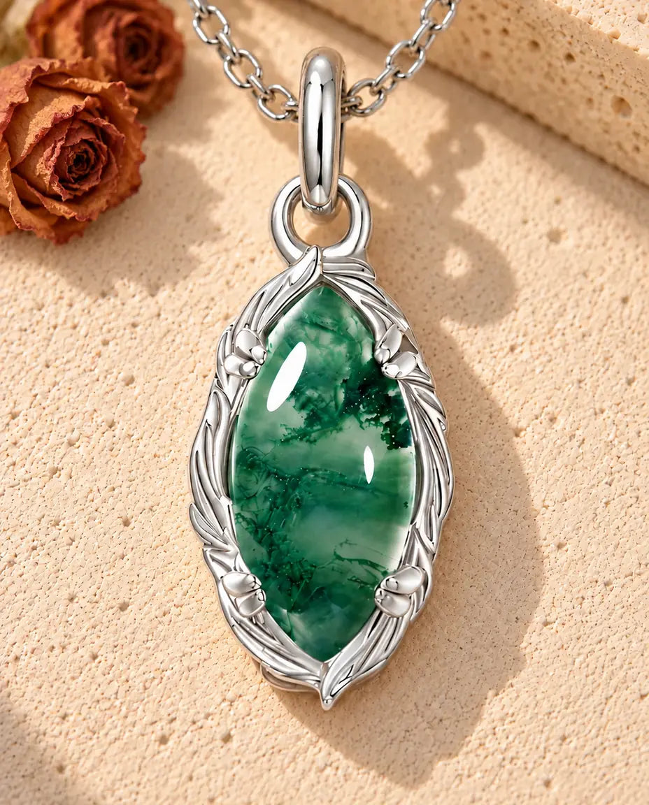 Marquise Moss Agate Necklace in 925 Sterling Silver - lying on a cream textured surface beside a travertine block