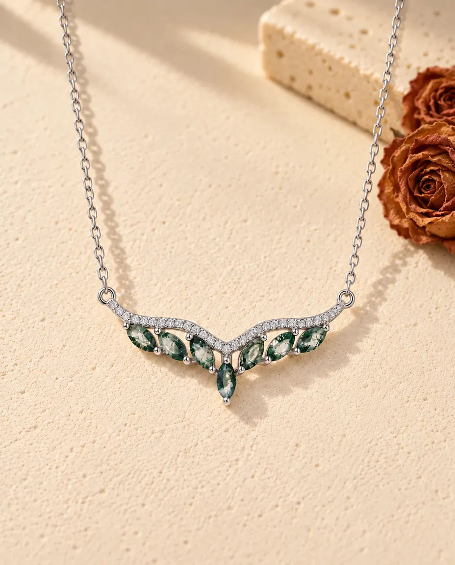 Moss Agate Chevron Necklace in 925 Sterling Silver - lying on a cream textured surface beside a travertine block
