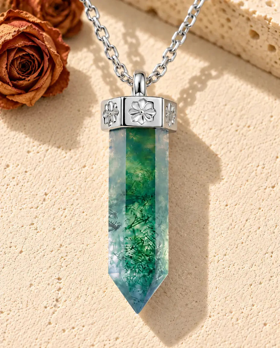 Moss Agate Point Necklace in 925 Sterling Silver - lying on a cream textured surface beside a travertine block