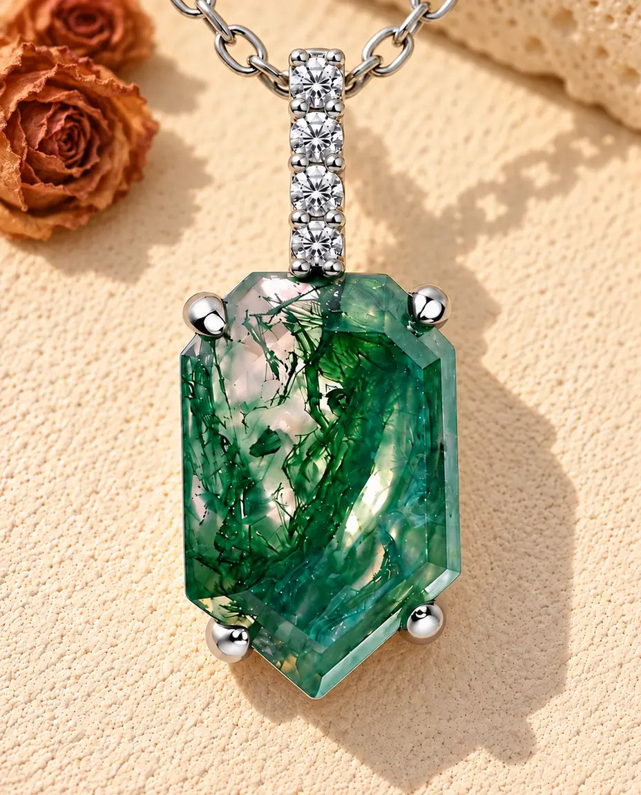 Moss Agate Shield Pendant Necklace in 925 Sterling Silver - lying on a cream textured surface beside a travertine block