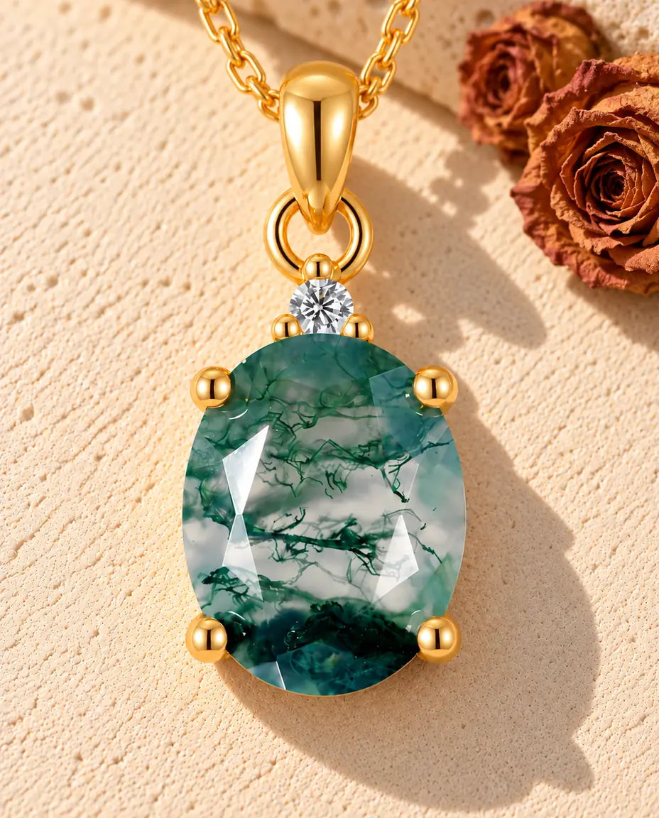 Oval Moss Agate Solitaire Necklace in Gold Plated 925 Sterling Silver - lying on a cream textured surface beside a travertine block
