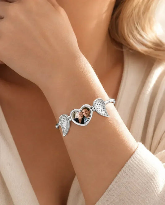 Woman wearing silver angel wing heart photo bangle in a garden