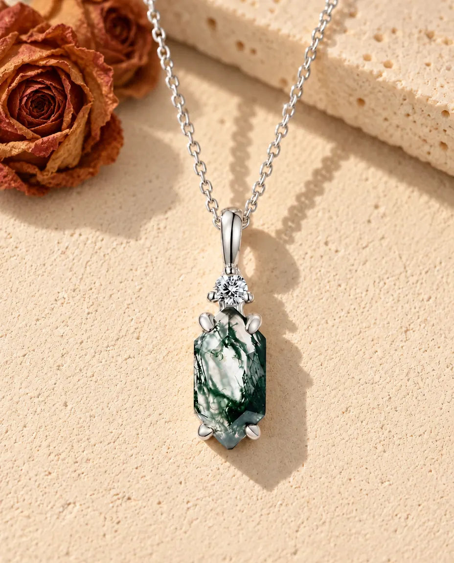 Hexagon Moss Agate Drop Necklace in 925 Sterling Silver - lying on a cream textured surface beside a travertine block