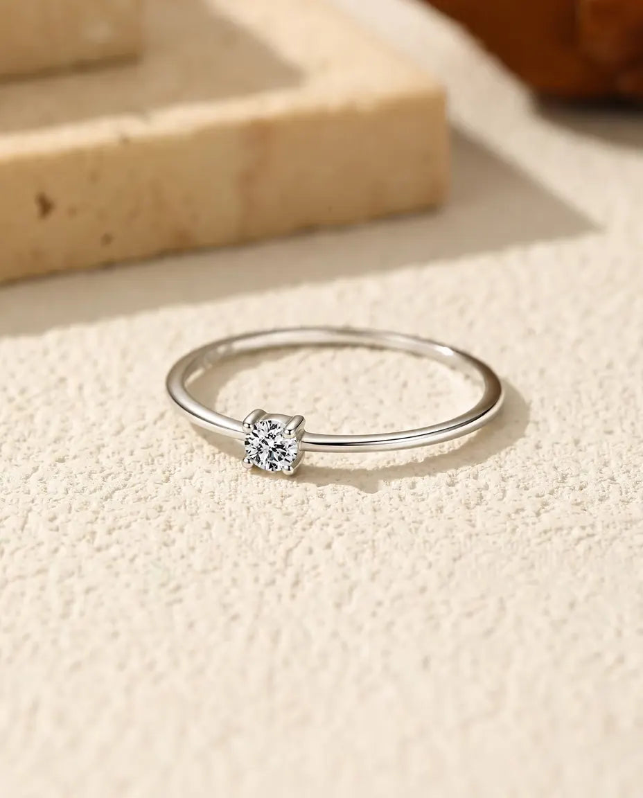 Dainty Moissanite Solitaire Ring in 925 Sterling Silver - lying flat on a cream textured surface