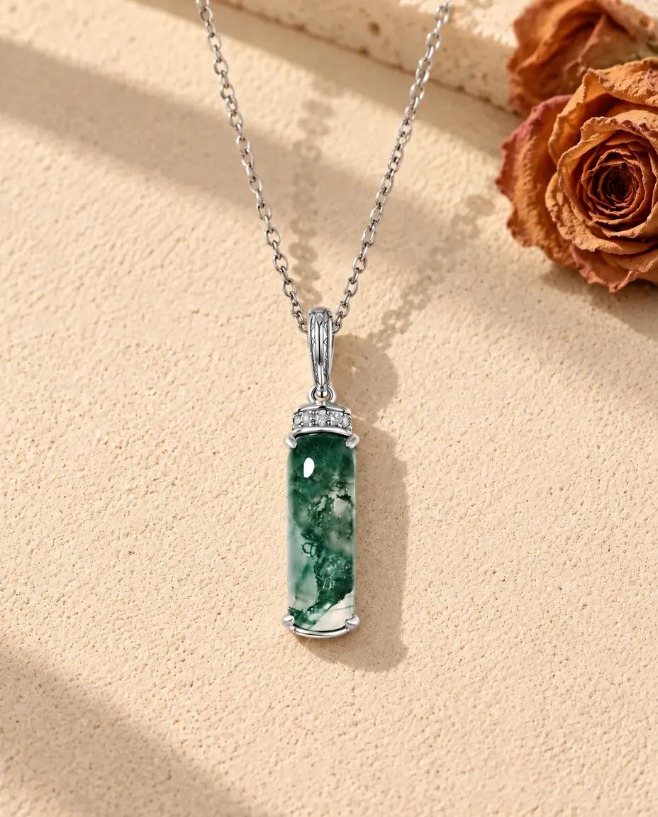 Moss Agate Bar Necklace in 925 Sterling Silver - lying on a cream textured surface beside a travertine block