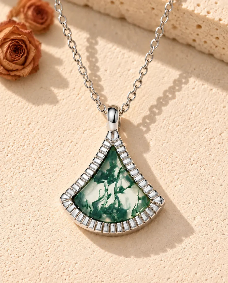 Moss Agate Fan Necklace in 925 Sterling Silver - lying on a cream textured surface beside a travertine block