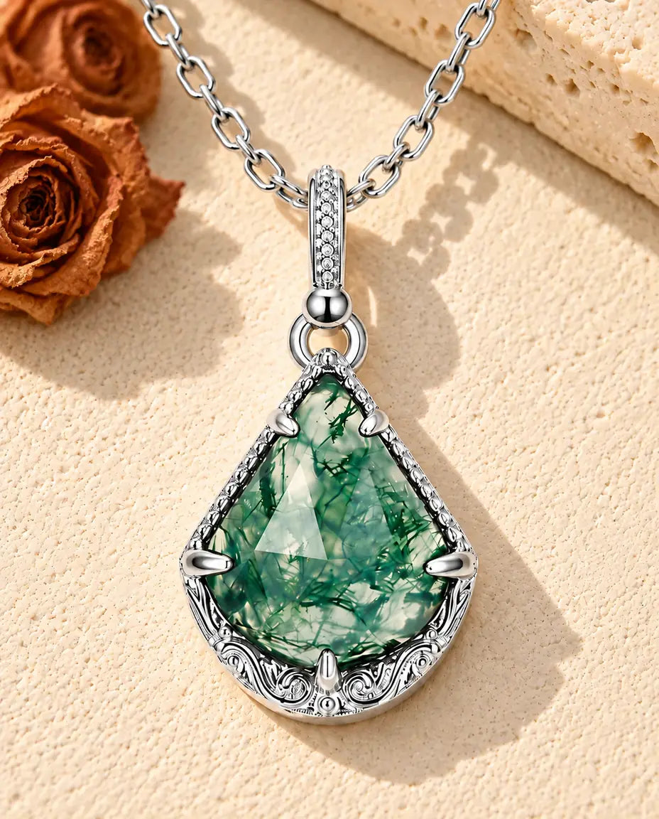 Moss Agate Shield Necklace in 925 Sterling Silver - lying on a cream textured surface beside a travertine block