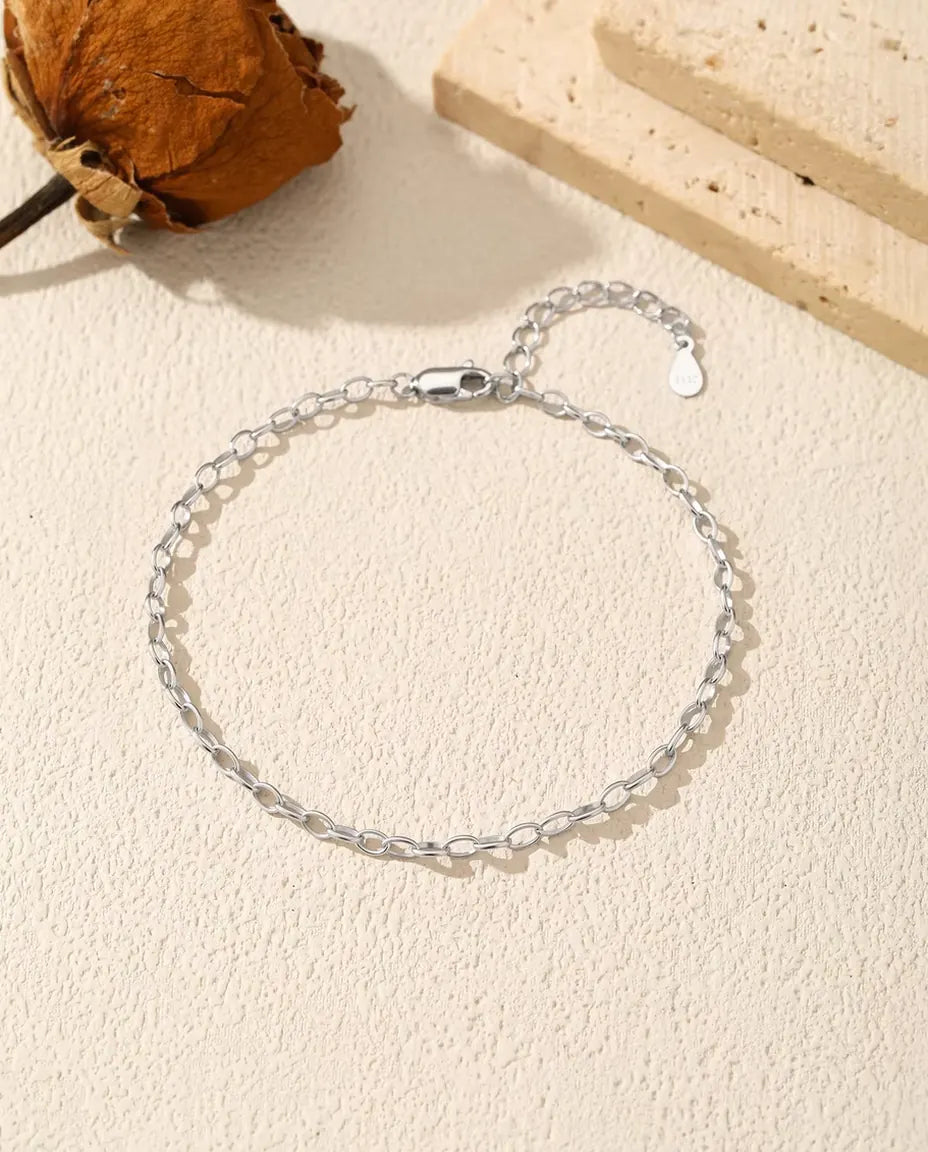 Oval Link Chain Bracelet in 925 Sterling Silver - laid flat on a cream textured surface with the clasp and extender