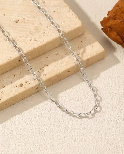 Oval Link Chain Necklace in 925 Sterling Silver - chain draped over a travertine slab, close-up