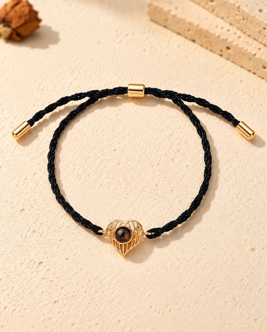 Top view of the gold tone angel wing heart photo projection bracelet with its adjustable slider