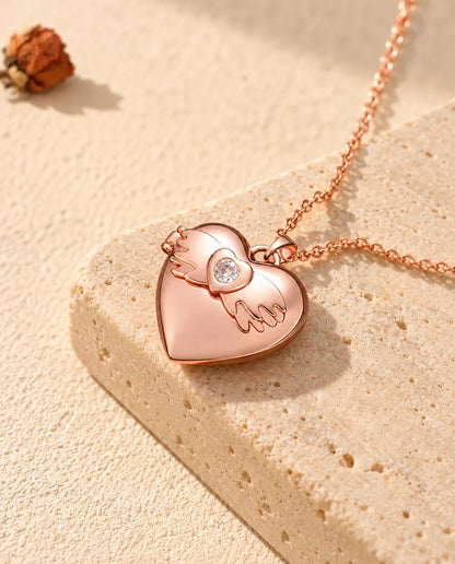 Rose gold tone angel wings heart photo locket necklace on travertine in warm sunlight