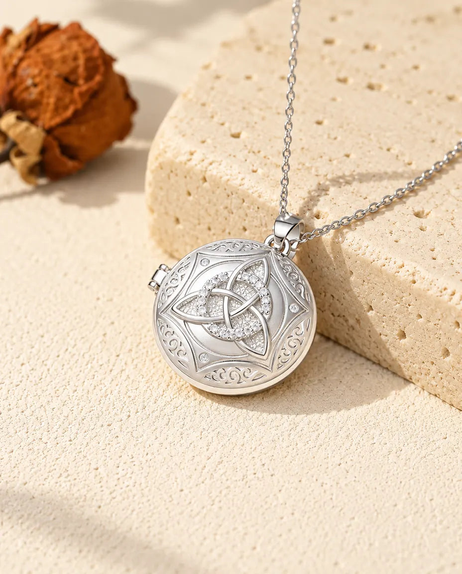 Personalised round Celtic knot photo locket necklace in silver with cubic zirconia, resting on a travertine block