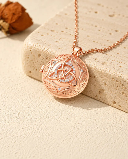 Rose gold tone Celtic knot photo locket with a pave circle resting on travertine