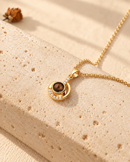Gold tone crescent moon projection necklace hanging over travertine