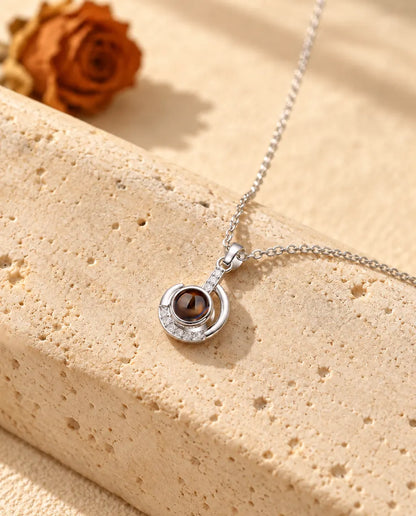 Silver tone crescent moon projection necklace hanging over travertine