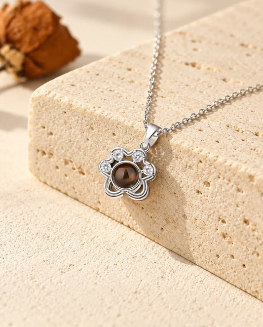 Personalised silver tone dainty paw print photo projection necklace on a travertine block