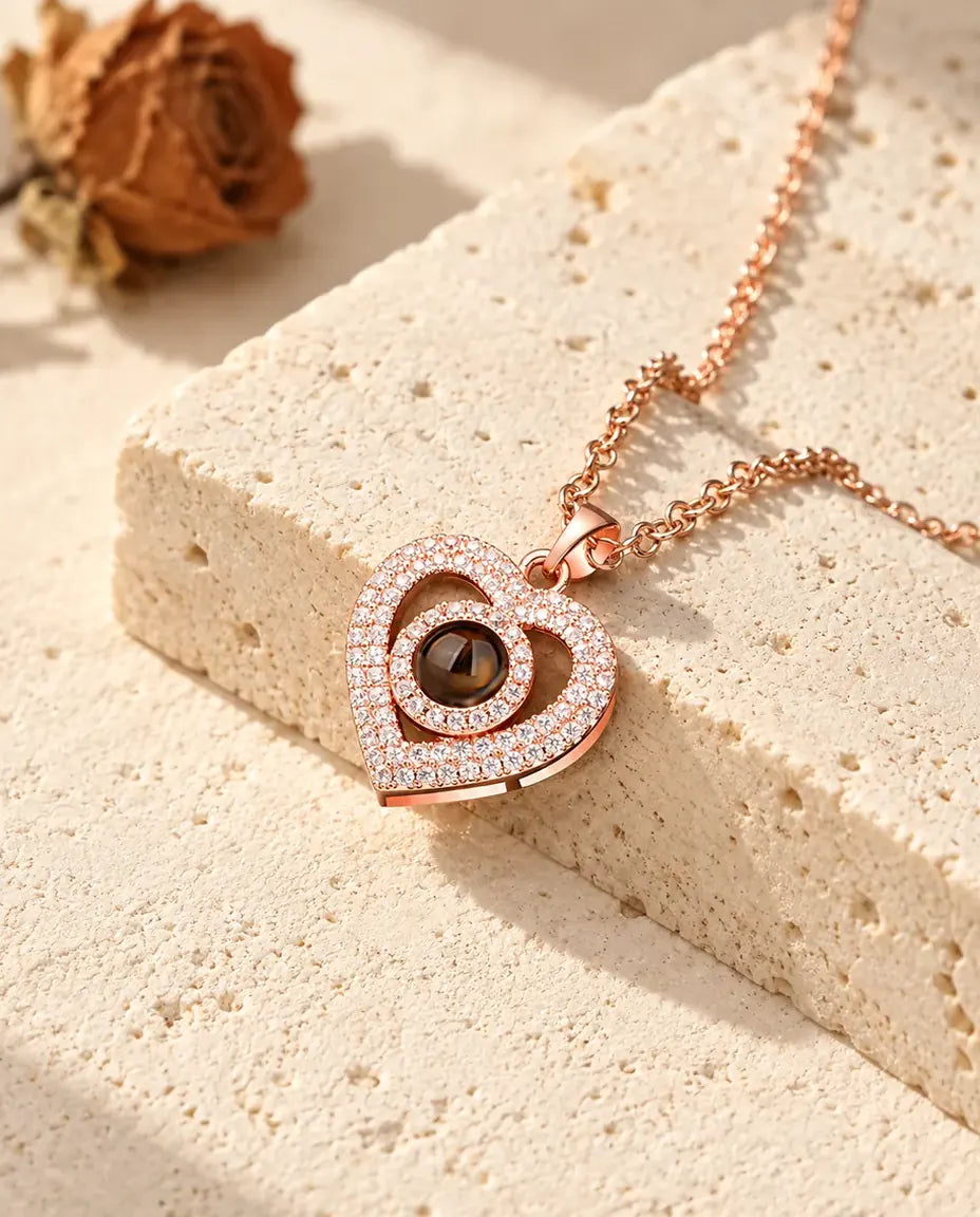Rose gold tone double heart pave pendant resting against a travertine block