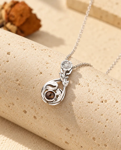 Silver tone flower teardrop projection necklace hanging over travertine