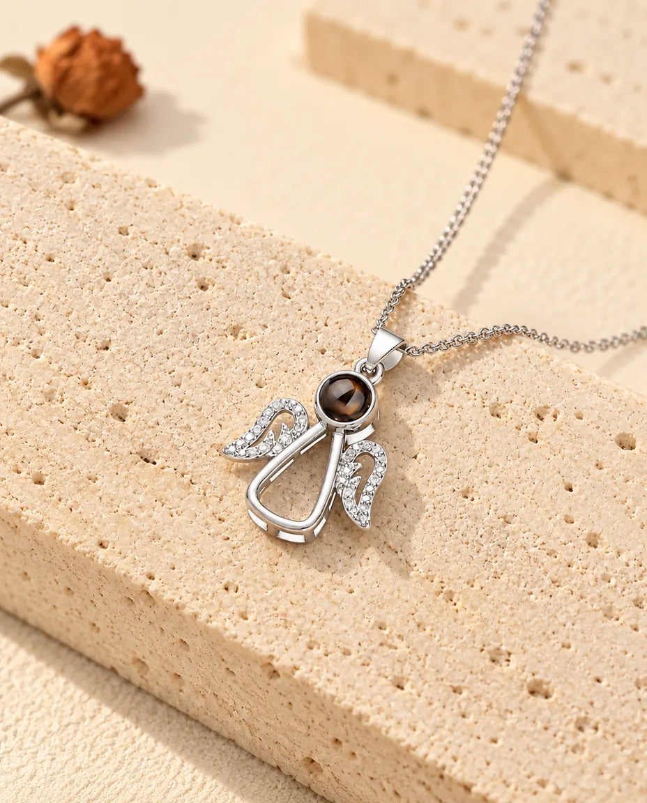 Personalised silver tone guardian angel photo projection necklace on a travertine slab