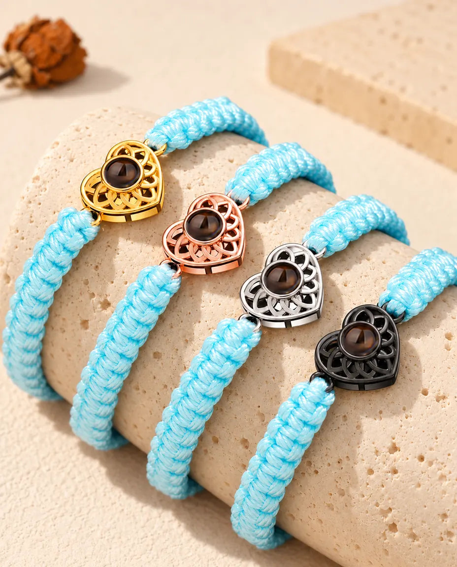 Light blue braided cord projection bracelets lined up on a travertine block in each charm colour