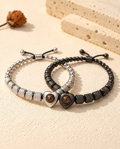 Silver tone and black heart projection bracelets linked together like two rings on plaster