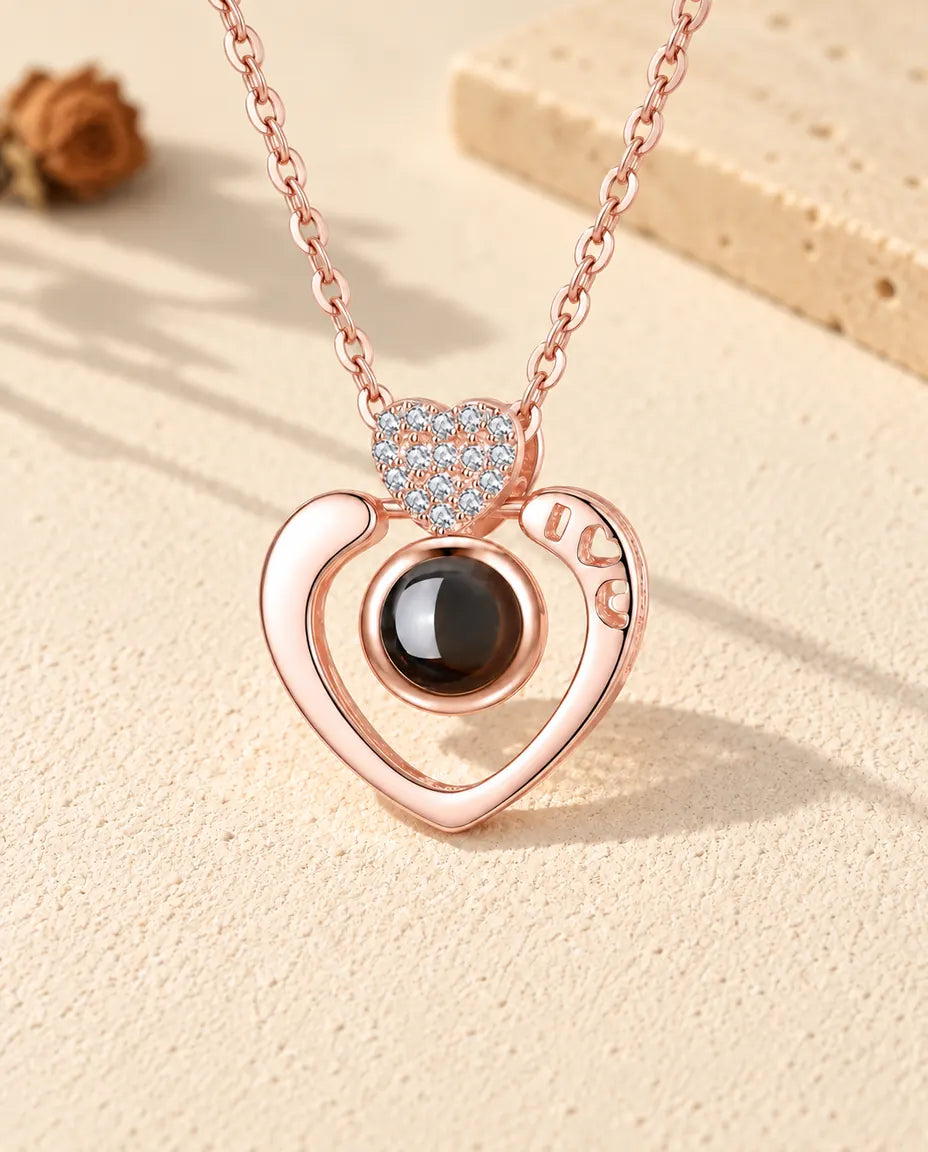 Front view of the rose gold tone open heart photo projection necklace
