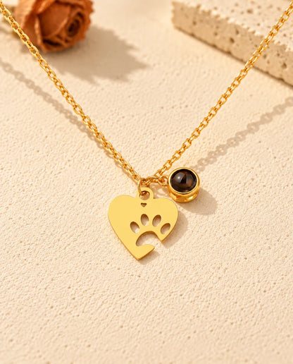 Front view of the gold tone paw print heart necklace with its projection stone charm