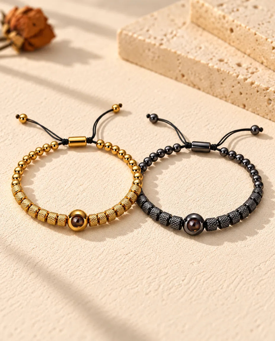 Personalised couples photo projection bracelets, a matching set of two textured bead bracelets in gold tone and black on cream plaster