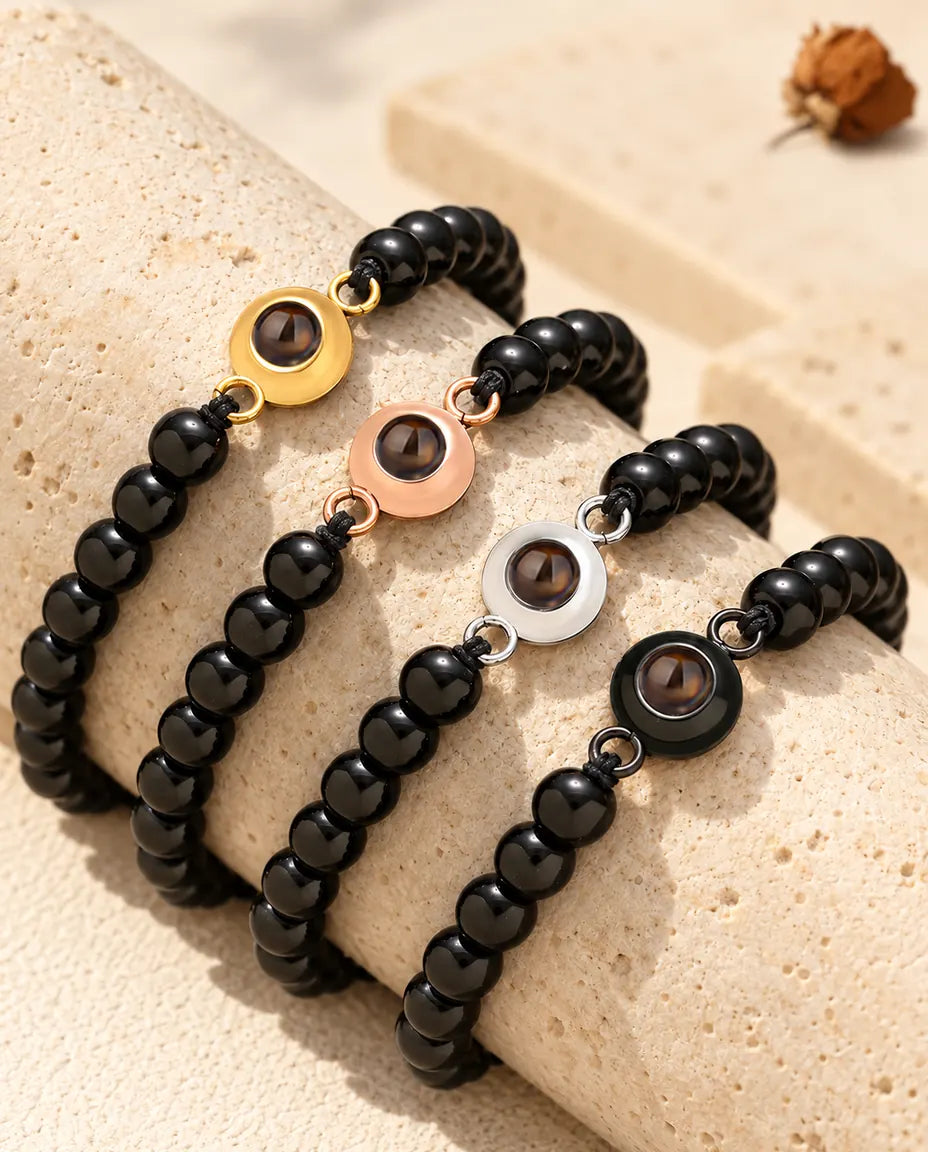 Glossy black bead projection bracelets in all four charm colours on a travertine block