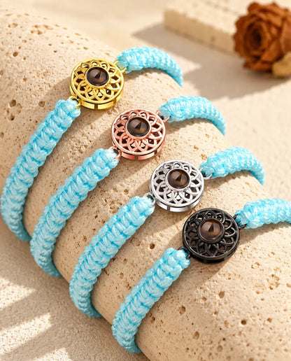 Light blue braided cord projection bracelets lined up on a travertine block in each charm colour