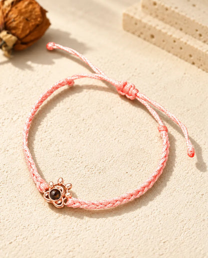 Rose gold tone paw charm on a pink braided cord with adjustable sliding knot