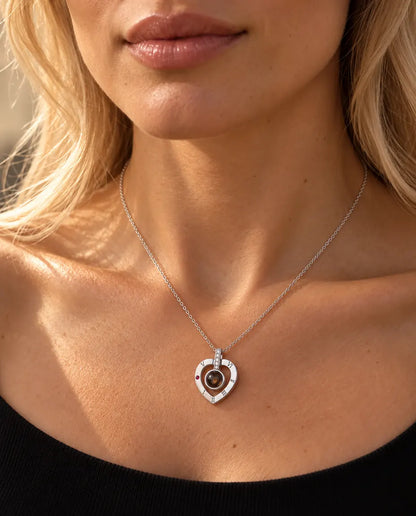 Woman in a black knit top wearing the silver Roman numeral heart projection necklace