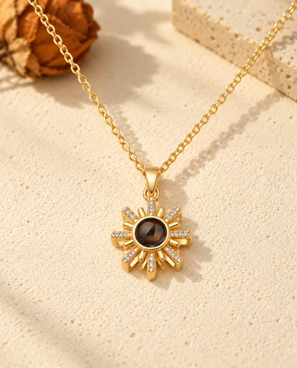 Front view of the gold tone sun pendant with the projection stone at its centre