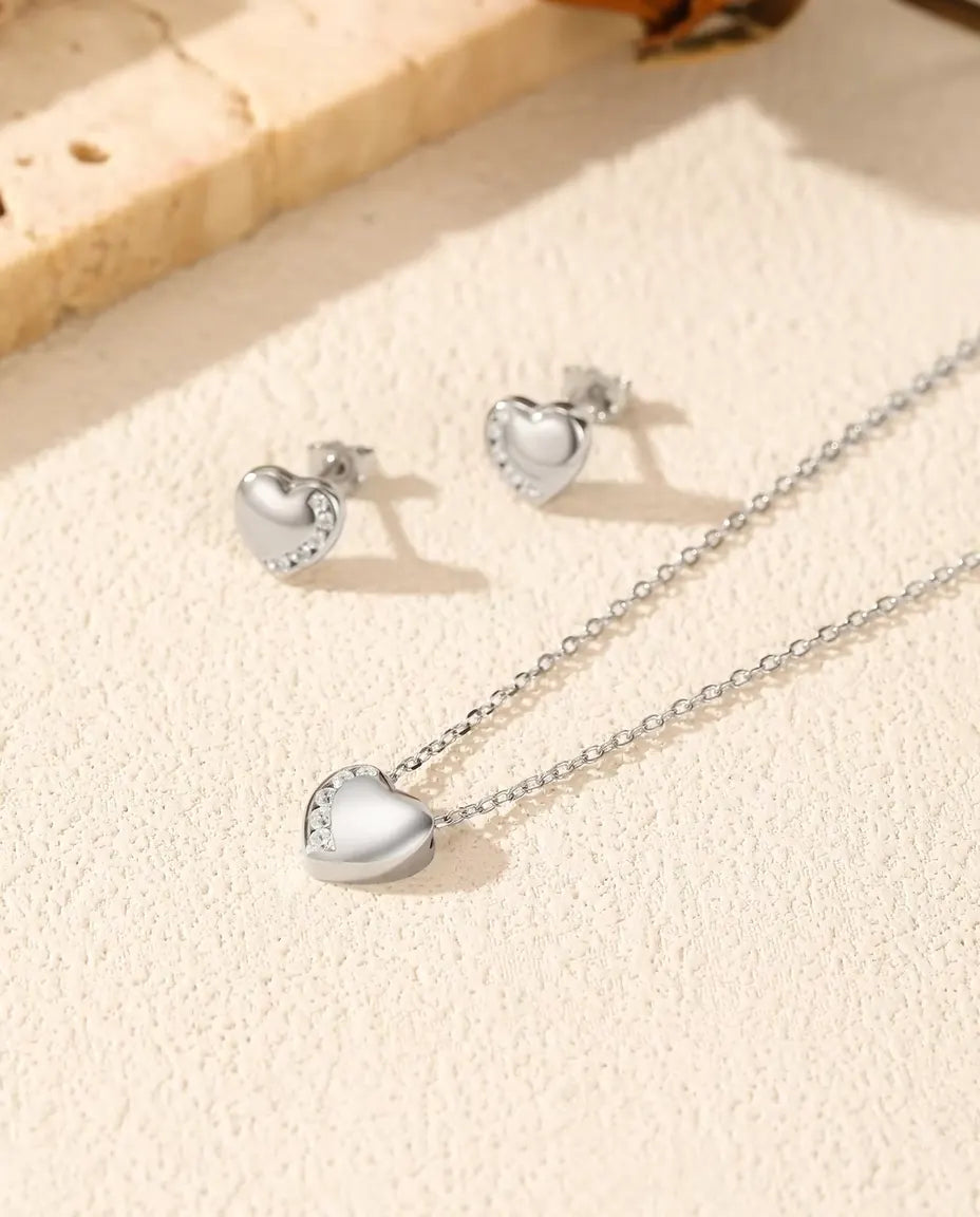 Heart Jewellery Set in 925 Sterling Silver - necklace and earrings laid together on a cream textured surface