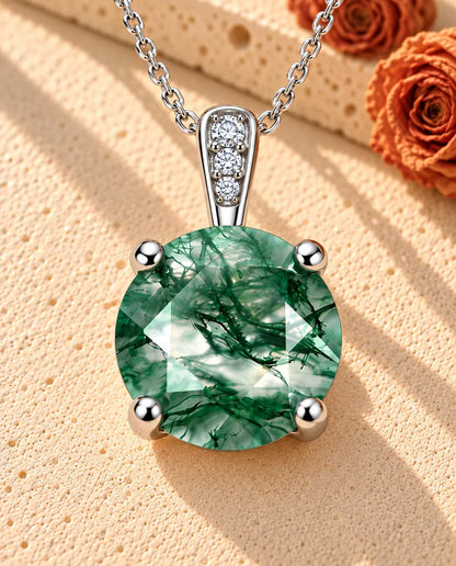 Round Moss Agate Solitaire Necklace in 925 Sterling Silver - lying on a cream textured surface beside a travertine block