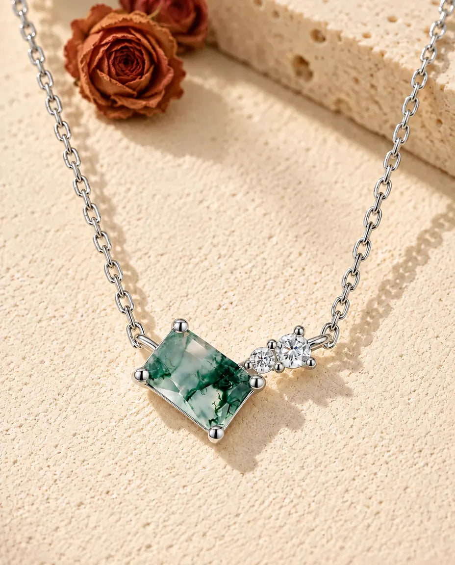 Moss Agate Bar Necklace in 925 Sterling Silver - lying on a cream textured surface beside a travertine block